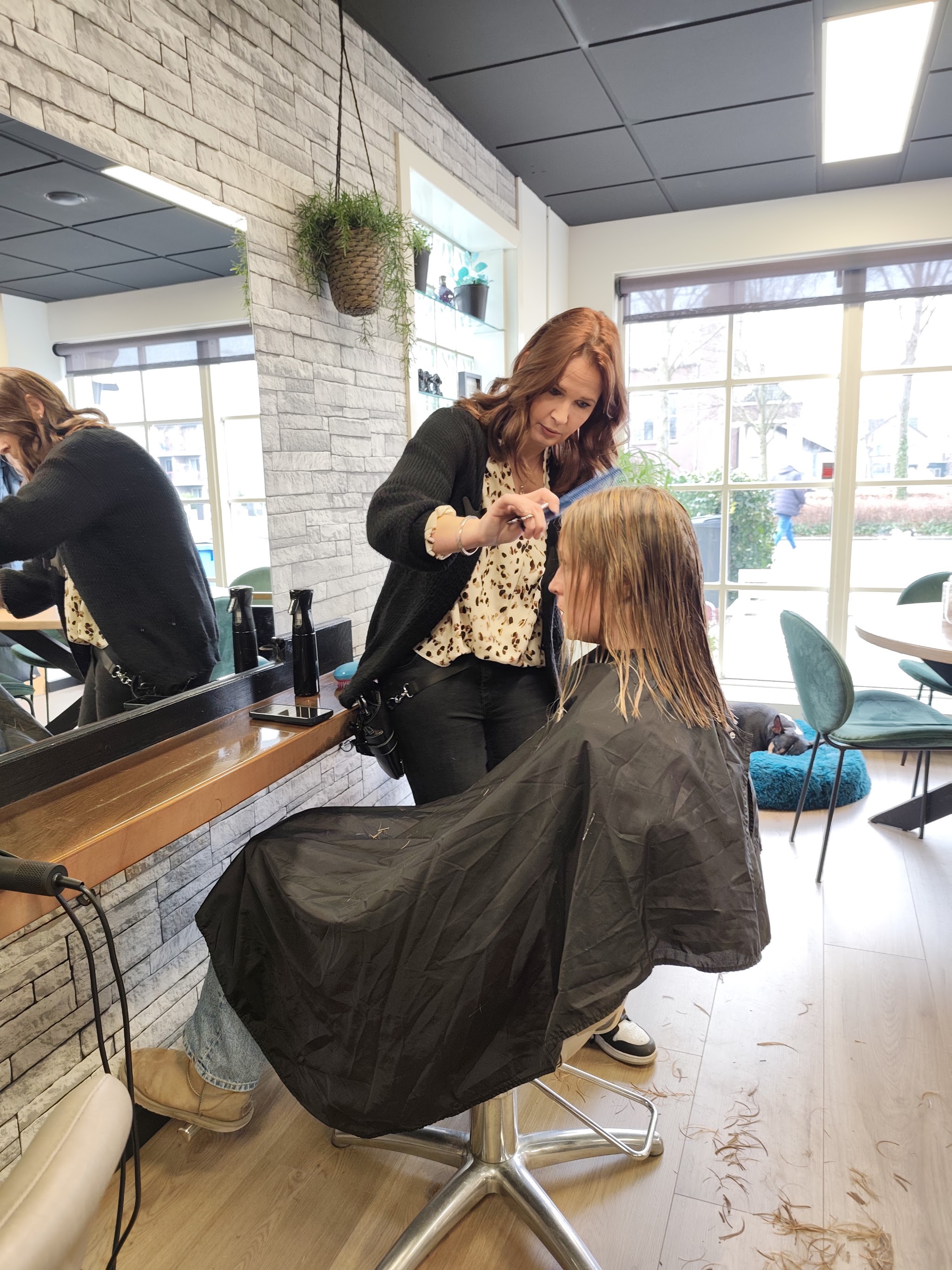 Een kapster werkt aan het haar van een klant in de salon